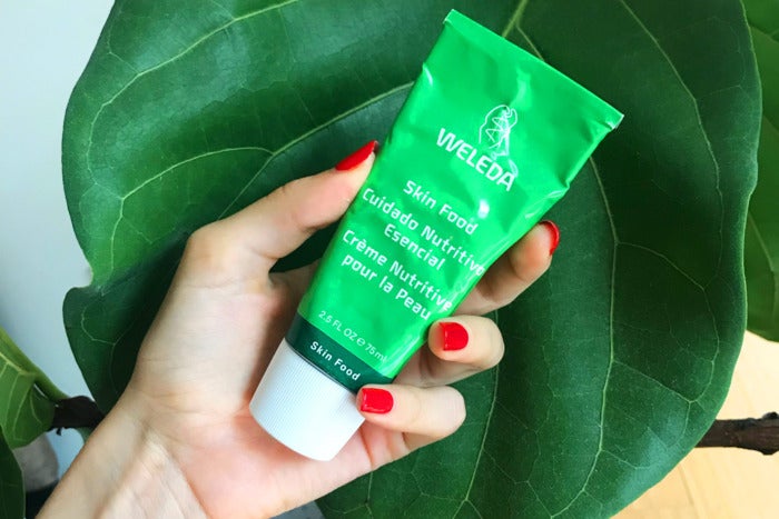 Person holding Weleda Skin Food container.